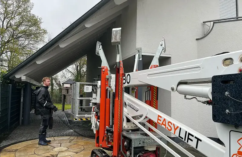 Mitarbeiter von FassadenProfis mit einem Hubsteiger unter einem Carport