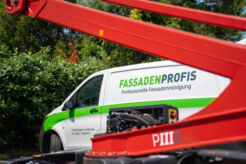 Firmenwagen von FassadenProfis neben dem roten Hubsteiger