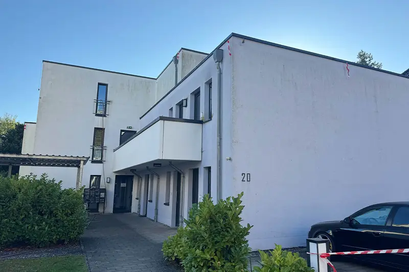 Eingangsseite des Studentenwohnheims in Lippstadt vor der Fassadenreinigung mit grauem Belag auf der weißen Putzfassade